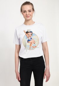 Weißes Baumwoll-T-Shirt mit einem bunten Grafikdesign eines Comiccharakters in einer Seemansuniform, der auf einem Rettungsring sitzt, umgeben von verspieltem Text.