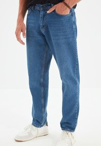 Vaqueros de denim azul con un corte recto, que cuentan con un cierre de botón clásico, diseño de cinco bolsillos y sutiles detalles de desgaste.