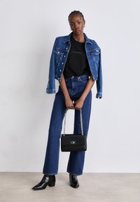 Blue denim jacket and jeans, black t-shirt with logo, black handbag with chain strap, and black ankle boots. Casual outfit.