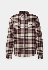 Camicia flanella a quadri con colori rosso, nero e beige; presenta una zip frontale, due tasche sul petto e dettagli con bottoni sulle maniche.