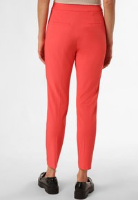 Pantalon corail ajusté avec deux poches arrière, fabriqué en tissu lisse, doté d'une taille mi-haute et de jambes fuselées.