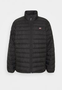 Doudoune matelassée noire Levi's avec fermeture éclair complète à l'avant, col montant et petit logo Levi's rouge et blanc sur la poitrine.