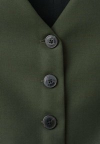 Tela verde oscuro con una textura suave que presenta tres botones redondos de color gris oscuro a lo largo de un escote en forma de V.
