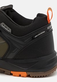 Adidași negri și măslinii cu o parte superioară din plasă texturată, protecție întărită pentru glezne și un tab de tragere portocalie. Design rezistent la apă.