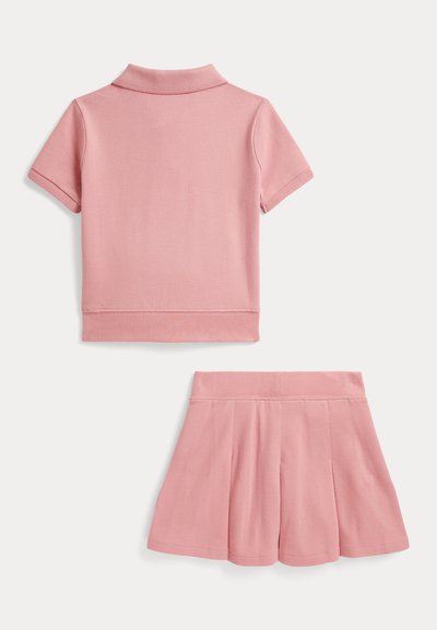 Polo rose à manches courtes et jupe plissée assortie posés à plat sur fond blanc, montrant la vue arrière des deux vêtements.
