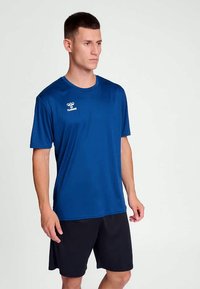 Camiseta deportiva azul hecha de tejido ligero, con cuello redondo y mangas cortas, acompañada de pantalones cortos negros.