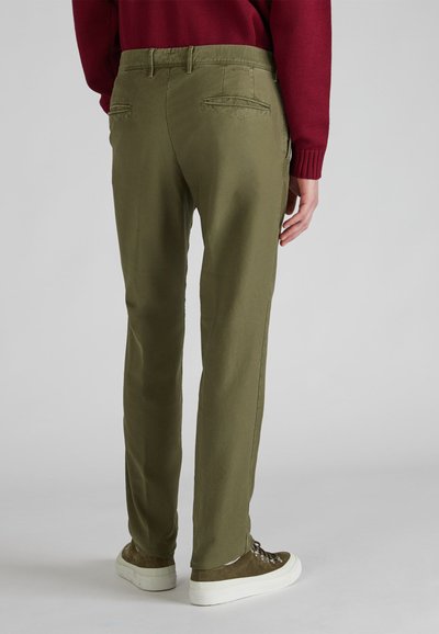 Oliwkowe bawełniane spodnie o prostym kroju, z dwiema tylnymi kieszeniami, noszone z brązowymi butami i bordowym swetrem.