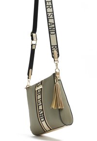 Zelená crossbody taška s béžovým a černým nastavovacím popruhem, charm s třásněmi a textem "RIVER ISLAND" na popruhu a předním panelu.