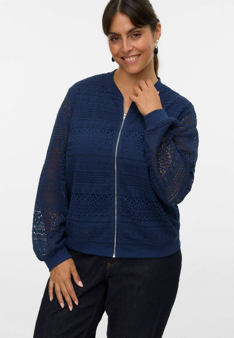 Giacca bomber blu navy con dettagli in pizzo, chiusura con zip, polsini e orlo a costine. Presenta motivi testurizzati su tutta la superficie.