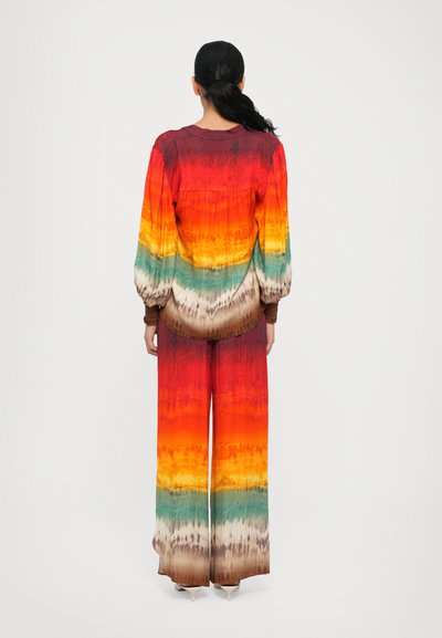 Zweiteiliges Outfit mit einem bunten Ombre-Muster: Schattierungen von Rot, Orange, Gelb, Grün und Braun; lockere Passform, lange Ärmel, weit geschnittene Hose.