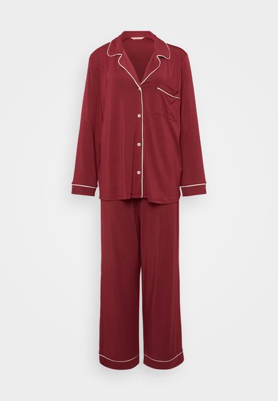 Conjunto de pijama bordeaux feito de tecido suave, com mangas longas, parte de cima com botões e bolso, e calças de perna larga, adornado com bainha branca.