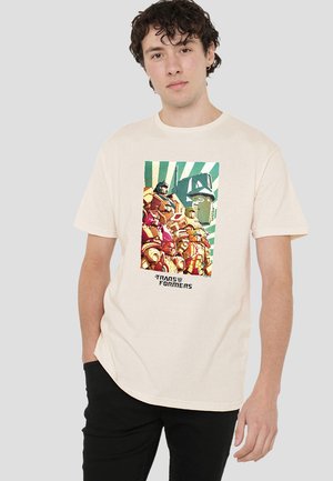 Cream-colored cotton t-shirt featuring a vintage-style graphic print of Transformers characters against a striped background.