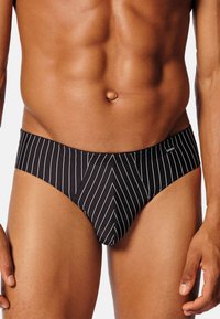 Slip a strisce nere con un motivo a zig zag, vita elastica e superficie liscia. Progettato per uno stile aderente.