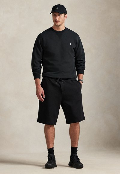 Μαύρο βαμβακερό φούτερ με λογότυπο στο στήθος, συνδυασμένο με μαύρο σορτς και καπέλο. Διαθέτει άνετη εφαρμογή και ζώνη μέσης με κορδόνι.