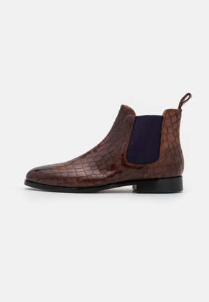 Bota Chelsea de cuero marrón con un patrón de cocodrilo texturizado, paneles laterales elásticos en azul oscuro y suela plana negra.