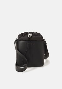 Czarna torebka crossbody z sztucznej skóry z wiązanym szczytem, srebrnymi elementami i gładką fakturą. Posiada nadruk logo oraz regulowany pasek.