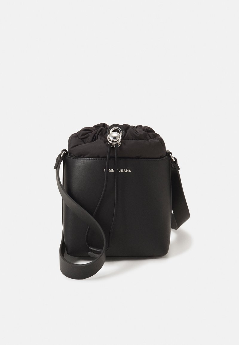 Czarna torebka crossbody z sztucznej skóry z wiązanym szczytem, srebrnymi elementami i gładką fakturą. Posiada nadruk logo oraz regulowany pasek.