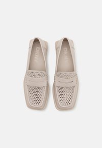 DKNY slip-on sko i lys beige, med perforerte detaljer på tåen og en glatt læroverdel. Rundet firkantet tå og polstret såle.