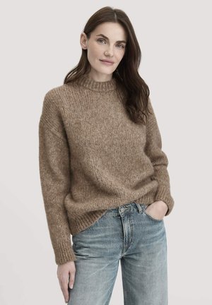 Brauner Strickpullover mit Rundhalsausschnitt, strukturiertem Stoff, lockerer Passform und gerippten Bündchen, kombiniert mit hellblauen Jeans.
