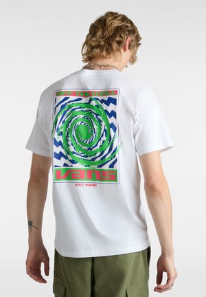 T-shirt bianca in cotone con un design grafico colorato sul retro, che include un vortice verde su uno schema a zigzag blu e testo rosso.