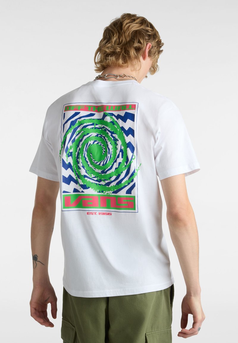 T-shirt bianca in cotone con un design grafico colorato sul retro, che include un vortice verde su uno schema a zigzag blu e testo rosso.