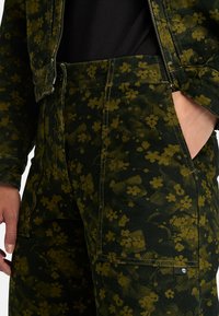 Groene spijkerjacket met bloemenpatroon, met een gestructureerd oppervlak en zichtbare stiksels, voorzien van een open rits en voorzakken.