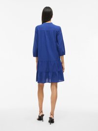 Plava haljina s višeslojnim dizajnom i rukavima do tri četvrtine, izrađena od lagane tkanine, s leđnom stremenicom i lepršavim A-linijom.
