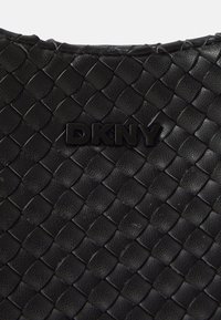 Zwart geweven leren handtas met een gestructureerd oppervlak. Voorzien van een geperst DKNY-logo in zwart aan de voorkant, wat het stijlvolle ontwerp benadrukt.