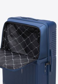 Valise rigide bleue avec un design à stries. L'intérieur présente un tissu noir avec un motif de logo "WITTCHEN" répété. La fermeture éclair est visible.