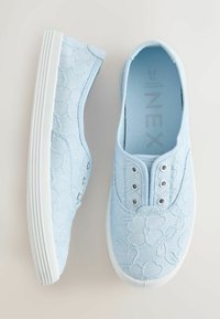 Baskets bleu clair à enfiler avec broderie florale blanche et semelles en caoutchouc blanches, vues de côté et de dessus.