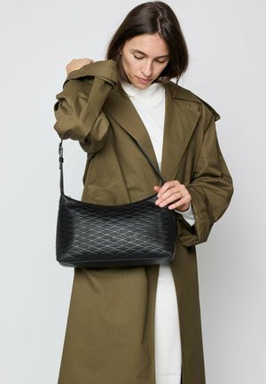 Schwarze gesteppte Handtasche mit geschwungener Form und strukturierter Oberfläche, ausgestattet mit einem langen, verstellbaren Riemen und einem Reißverschluss.