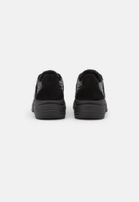 Schwarze Sneakers mit einem Obermaterial aus Wildleder und Mesh, runderzehige Form, gepolstertem Absatz und strukturiertem Gummi-sohle, ausgelegt für Komfort und Unterstützung.