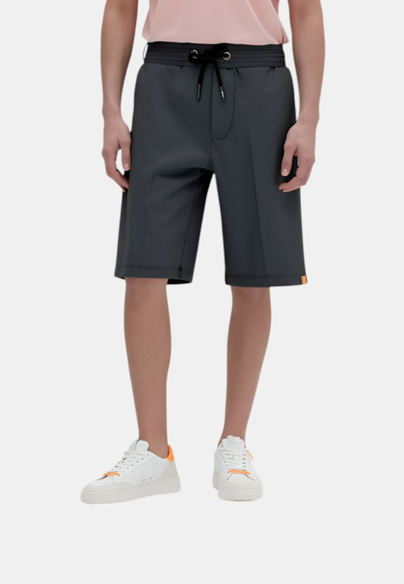 Pantaloni corti grigi realizzati in un materiale liscio, lunghi fino al ginocchio, con una vita regolabile tramite coulisse e dettagli arancioni all'orlo, abbinati a sneaker bianche.