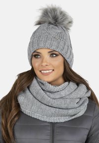 Grijze gebreide muts met een bontpompon en een bijpassende grijze gebreide sjaal. Beide items hebben dikke texturen in een zachte, warme stof.