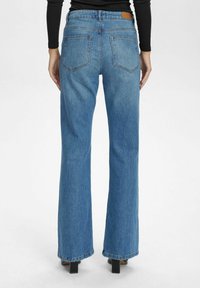 Svetlo modri traper hlače s flared krojem in srednjim pasom, z dvema zadnjima žepoma in usnjenim trazorjem na pasu.