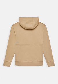 Haut à capuche beige avec cordon de serrage, manches longues et poche kangourou. Le tissu semble doux avec une texture lisse et un design minimaliste.