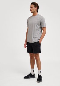 Grå T-shirt med korte ærmer, sorte shorts med lommer, sorte sportssko og hvide strømper med sort mønster; enkelt og funktionelt design.