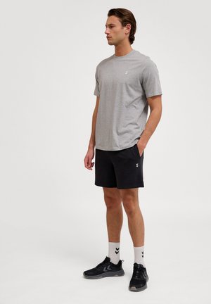Szara koszulka polo z krótkim rękawem, czarne spodenki z kieszeniami, czarne buty sportowe i białe skarpetki w czarny wzór; prosty i funkcjonalny design.