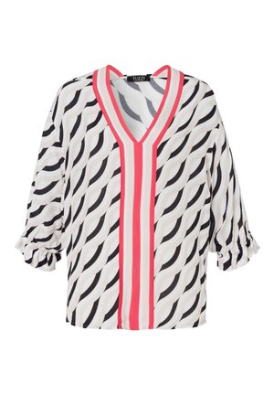Weiße Bluse mit schwarzen und grauen Wellenmustern; hat einen tiefen V-Ausschnitt und pinke senkrechte Streifen; dreiviertel Ärmel mit Rüschensaum.