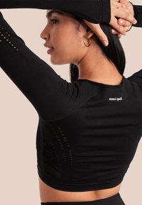 Zwarte lange mouw top met een aansluitend ontwerp, textuur mesh panels aan de zijkanten en een discreet logo op de achterkant. Glad materiaal.