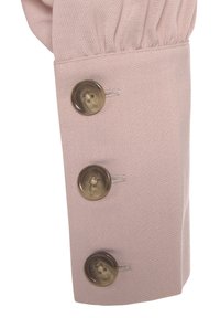 Roze stoffen manchet met drie grote, ronde, donkere knopen. Gladde textuur en op maat gemaakte ontwerp met geplooide details boven de manchet.