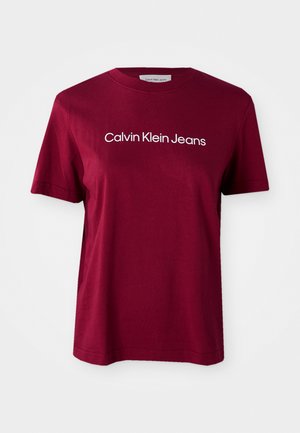 Burgundy cotton t-shirt with short sleeves, featuring a white “Calvin Klein Jeans” logo across the chest and a classic crew neckline.