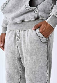 Sudadera gris con un acabado texturizado, con cuello redondo y dobladillo acanalado. Combinada con joggers gris a juego con bolsillos laterales.