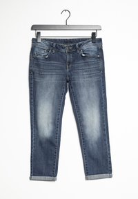 Pantalones vaqueros de denim azul oscuro colgados en una percha, con un lavado desgastado, diseño de cinco bolsillos, cremallera frontal y puños enrollados en los tobillos.
