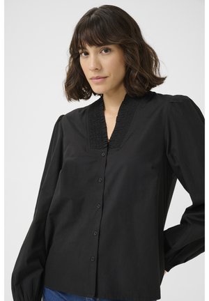 Blusa nera con un colletto strutturato e plissettato, maniche lunghe e chiusura con bottoni sul davanti. Realizzata in tessuto morbido, presenta un taglio comodo.