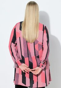 Langærmet skjorte med geometrisk mønster i pink, sort og grå. Letvægtsstof med løs pasform og manchetter med knapper.