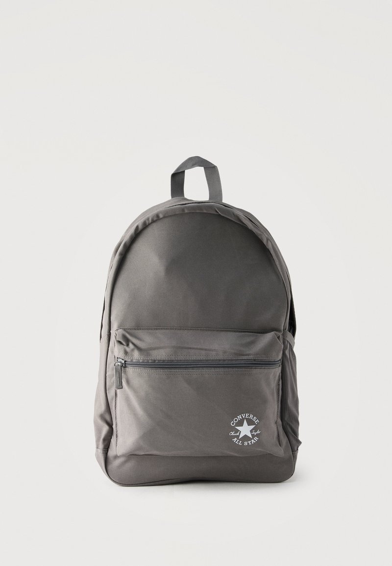 Γκρι σακίδιο πλάτης Converse All Star με μπροστινή τσέπη με φερμουάρ και κορυφαία λαβή μεταφοράς σε μονόχρωμο ανοιχτό φόντο.