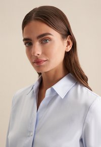 Lichtblauwe button-up overhemd met een klassieke kraag, gemaakt van gestructureerde stof, met een gladde textuur en een subtiele glans.