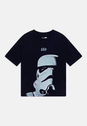 Černé bavlněné tričko s potiskem helmy Stormtroopera, nad kterým je logo "GAP". Krátké rukávy a pohodlný střih.