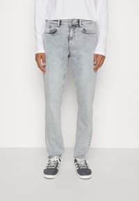 Ljusblå denimjeans med rak passform, utrustad med fem fickor och subtila blekningar. Kombinerat med svarta och vita sneakers.